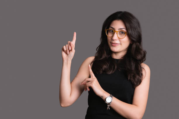 Young woman smiling and gesturing to copy space