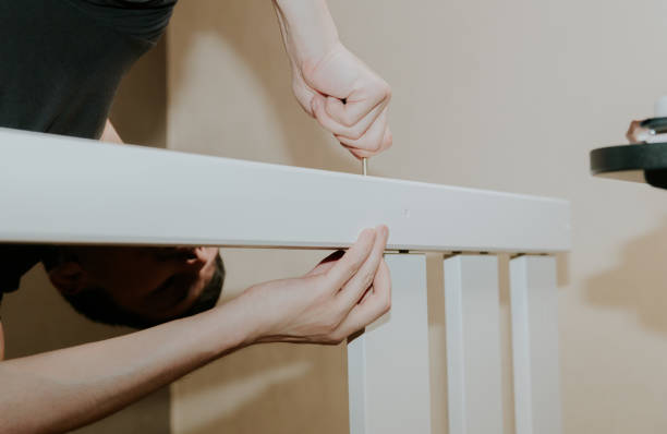 istock A young man threads a screw through a hole in the side of a bunk bed. 2154424727