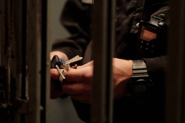 Hands of guard with keys behind mesh