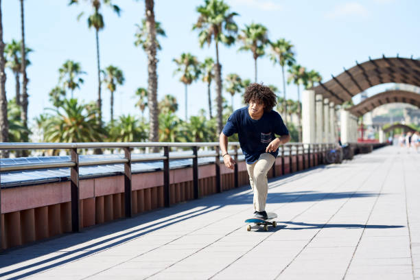 istock Boy sliding his skateboard along sunny sidewalk. 2154430089