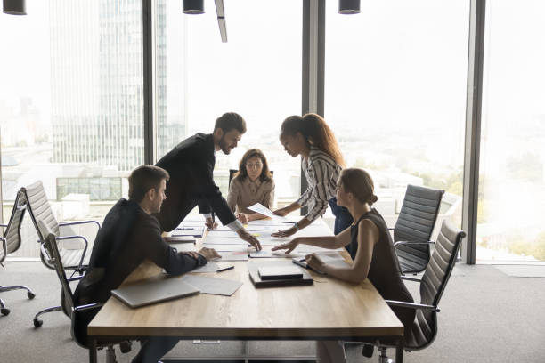 istock Multiethnic project colleagues discussing paper reports at meeting table 2154431195
