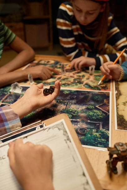 Hand of youthful girl holding group of dice before throwing them on board with picture of magic forest during tabletop game