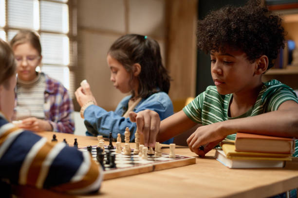 istock Serious boy moving pawn on chess board 2154432837