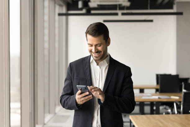 istock Cheerful business professional man typing on cellphone in office space 2154434028