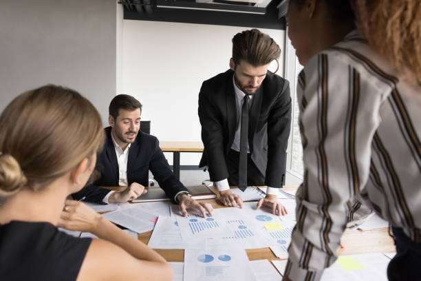 istock Focused business team analyzing sales together, reviewing paper reports 2154434214