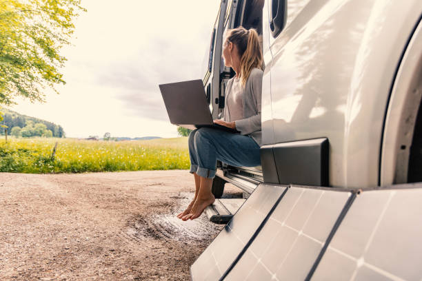 istock Woman working from her camper van on a laptop computer, solar panel is visible next to her 2154440866