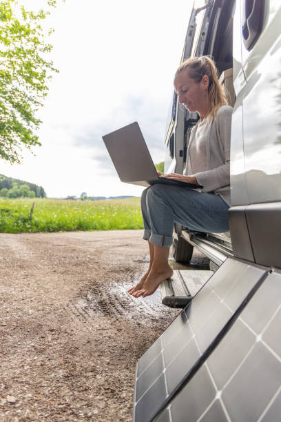 istock Woman working from her camper van on a laptop computer, solar panel is visible next to her 2154440872