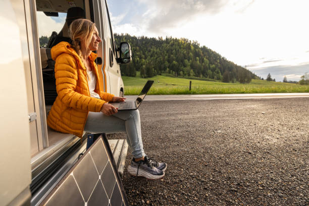 istock Woman working from her camper van on a laptop computer, solar panel is visible next to her 2154441796