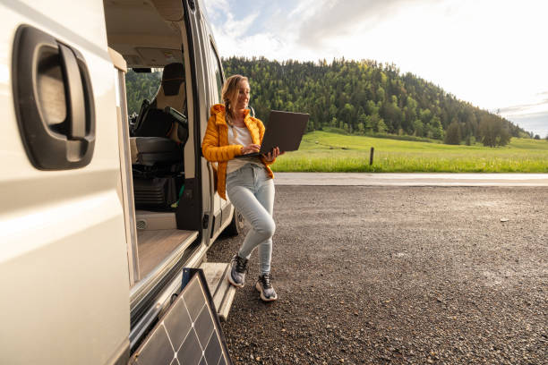 istock Woman working from her camper van on a laptop computer, solar panel is visible next to her 2154441797