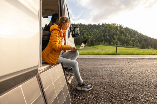 istock Woman working from her camper van on a laptop computer, solar panel is visible next to her 2154441803