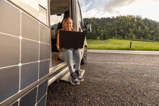 istock Woman working from her camper van on a laptop computer, solar panel is visible next to her 2154441832