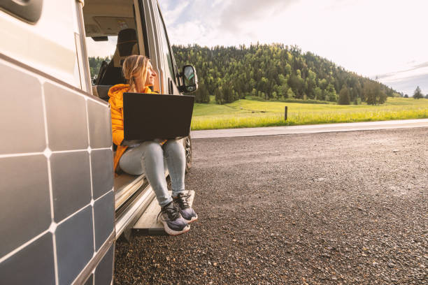 istock Woman working from her camper van on a laptop computer, solar panel is visible next to her 2154441838