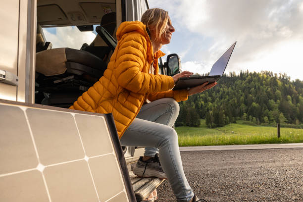 istock Woman working from her camper van on a laptop computer, solar panel is visible next to her 2154442693