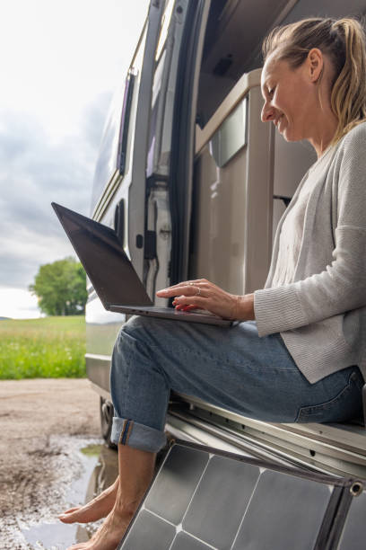 istock Woman working from her camper van on a laptop computer, solar panel is visible next to her 2154443047