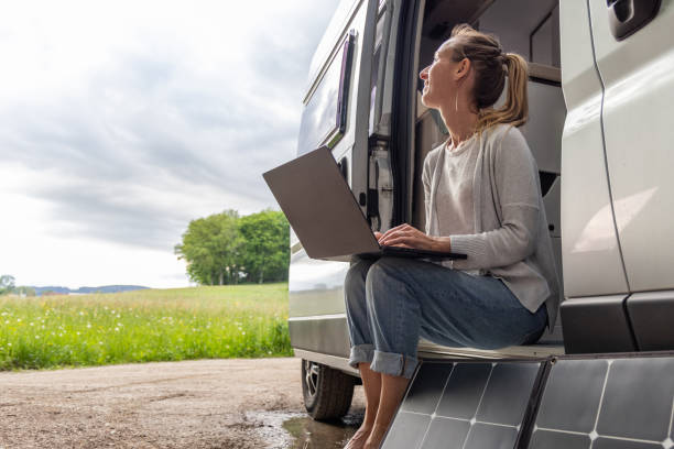 istock Woman working from her camper van on a laptop computer, solar panel is visible next to her 2154443048