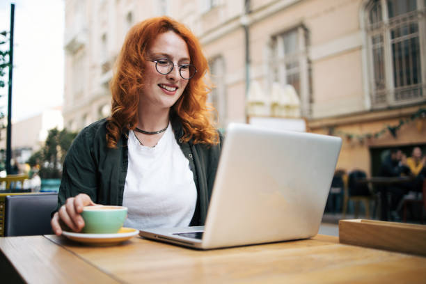 istock Happy young redhead woman relax in cafe  and drinking coffee. She using lap top. 2154447701