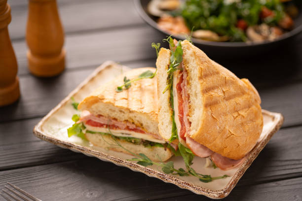 istock Two pieces of sandwich with bacon, tomatoes, cheese and lettuce on a plate 2154451143