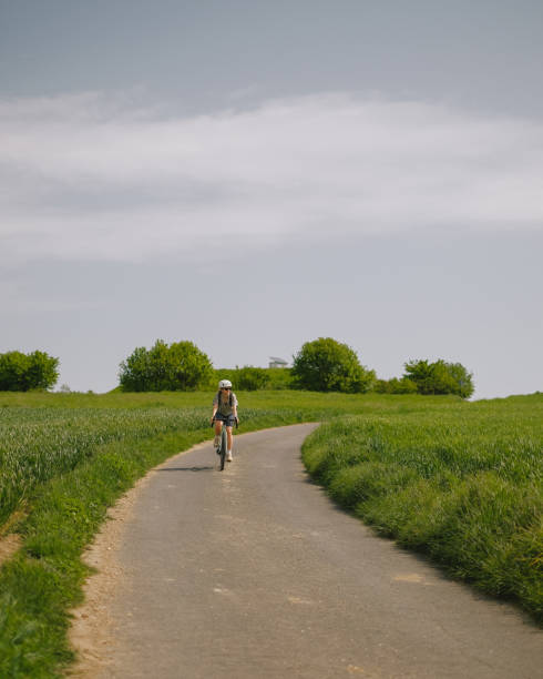 istock Road bicyclist rides through rural landscape 2154453323