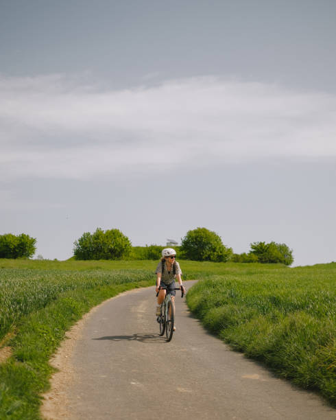 istock Road bicyclist rides through rural landscape 2154453405