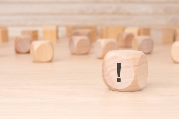 茶色の背景に側面に黒の感嘆符が付いた小さな木製のブロック - 注意点 ストックフォトと画像