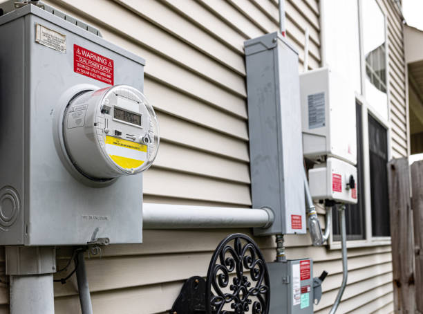 The utility electricity bill meter is connected to the photovoltaic system inverter and quick disconnect box, providing a dual power supply. Stickers indicating the solar panel source are placed according to regulations.