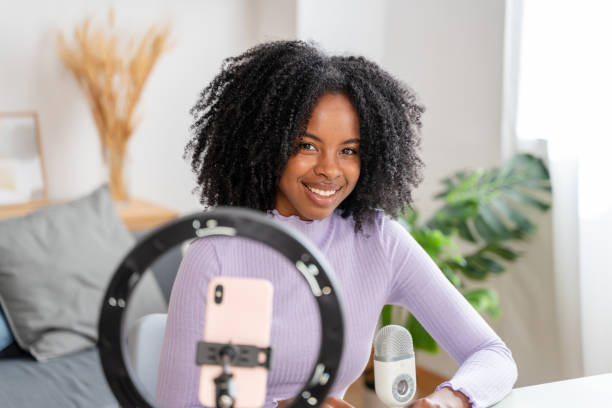 istock Smiling woman creating content with smartphone and ring light 2154460517