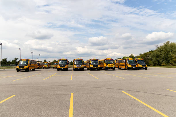Yellow school buses lined up in an empty parking lot - under a partly cloudy sky