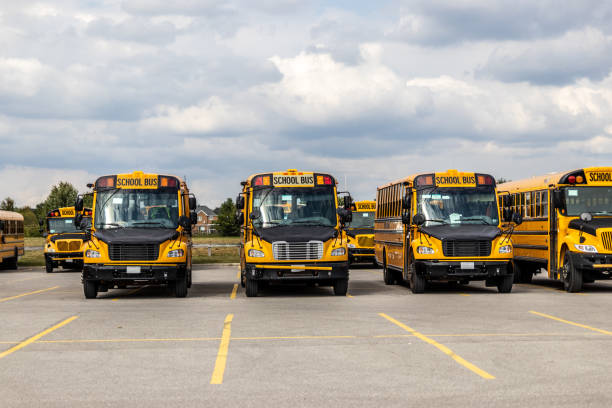 istock Yellow school buses lined up in an empty parking lot - under a partly cloudy sky 2154461222