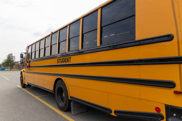 istock Bright yellow school bus parked in open area - clear sky above - STUDENT displayed on side - red stop sign 2154461234