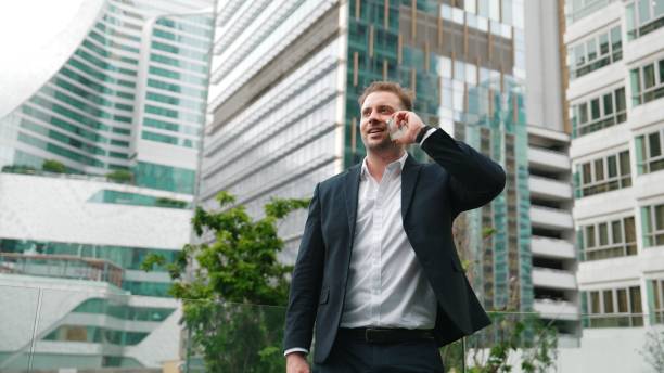 istock Businessman talking to team by using phone while standing at skyscraper. Urbane. 2154461649