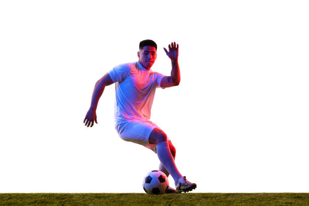 Teenage soccer player kicking ball on a soccer field
