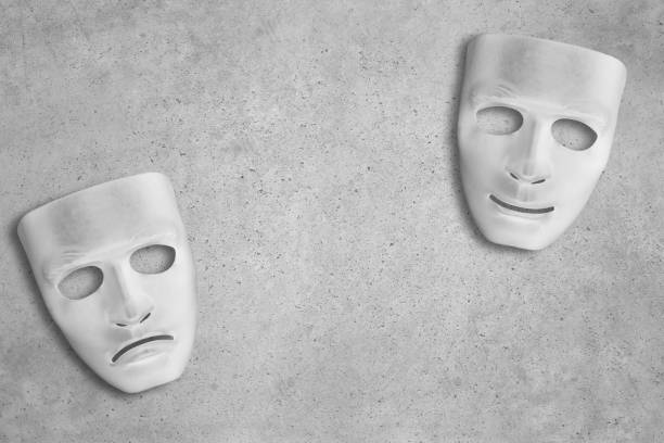 White theatre masks on a cement background