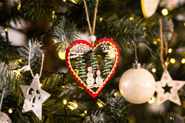 A close-up shot of a Christmas decoration hanging from a tree. The decoration is circular and has two snowmen within it.Videos are available similar to this scenario.