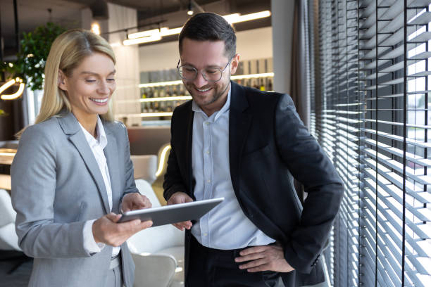 istock Man and woman standing with tablet discussing professional ideas 2154471877