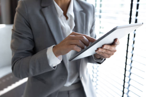 istock Businesswoman using digital tablet while standing near window in office 2154471893