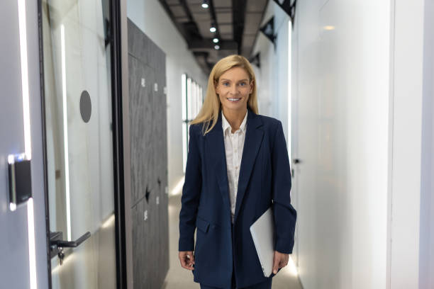 istock Confident businesswoman holding laptop while standing in modern office hall 2154472083