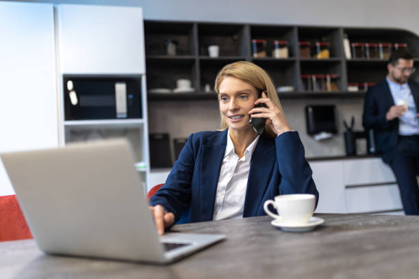 istock Woman professional manager using laptop while having phone conversation with cup of coffee in office 2154472086