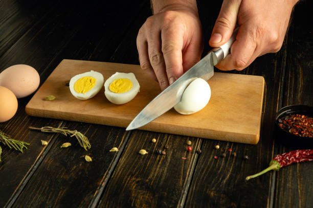 istock A cook cuts a boiled egg with a knife before preparing an eggs dish. Low key calorie diet concept on kitchen table. Place for advertising 2154472193