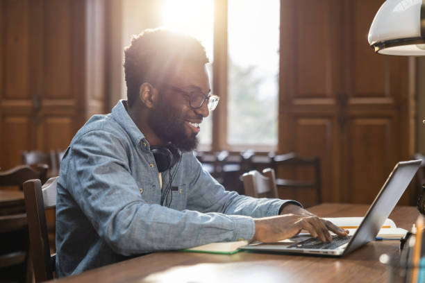 istock Dark-skinned young man sitting at the laptop in the library 2154478914