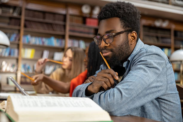 istock Curly-haired bearded african american man in the library looking thoughtful 2154479013