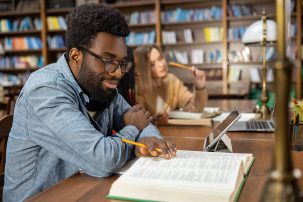 istock Curly-haired bearded african american man in the library looking thoughtful 2154479020