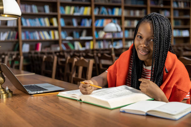 istock Long-haired young woman in red clothes studying in the library 2154479094