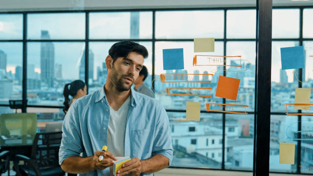 istock Businessman uses sticky notes at glass wall to brainstorming idea. Tracery 2154483206