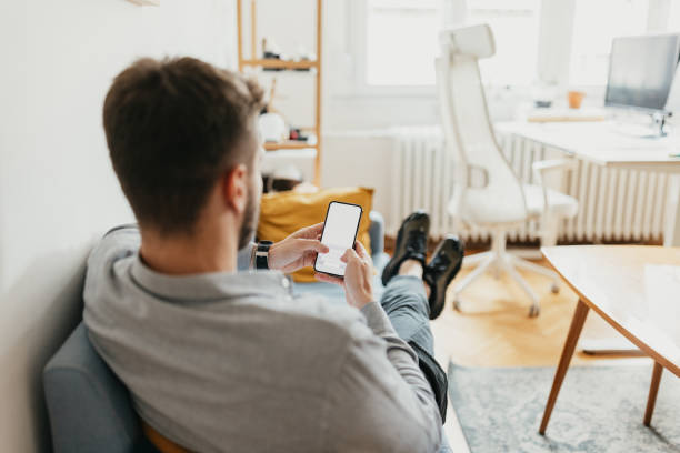 istock Man holding phone with blank screen on couch 2154483796