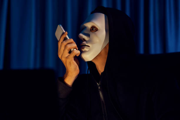 istock White criminal anonymous mask calling to IT owner to threaten ransom. Pecuniary. 2154483801