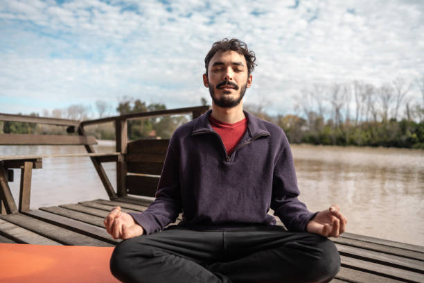 istock Young man meditating on the pier outdoors 2154495332