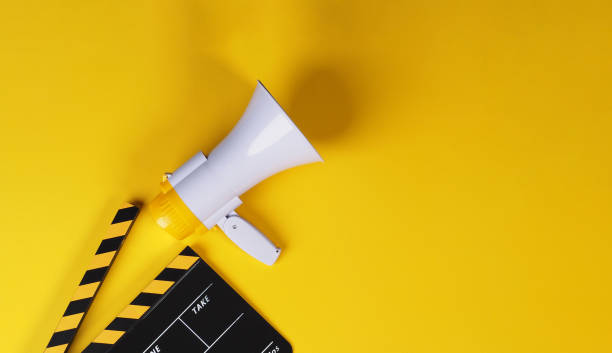 istock Clapper board in yellow and black with megaphone on yellow background. 2154497216