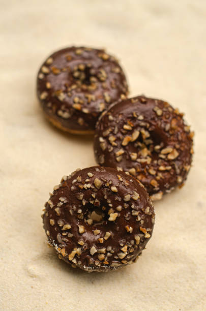 istock Three chocolate donut with sprinkles on beige background. 2154497333