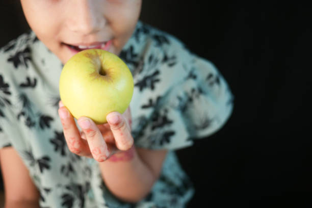 Above view of little girl eating an apple in autumn park