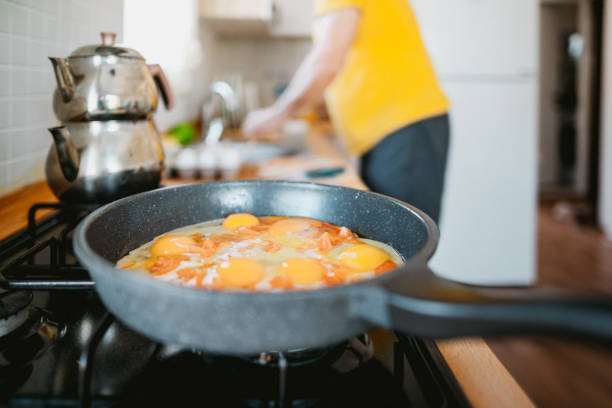 Cooking healthy breakfast: tasty fried sunny-side up eggs with tomatoes and cheese